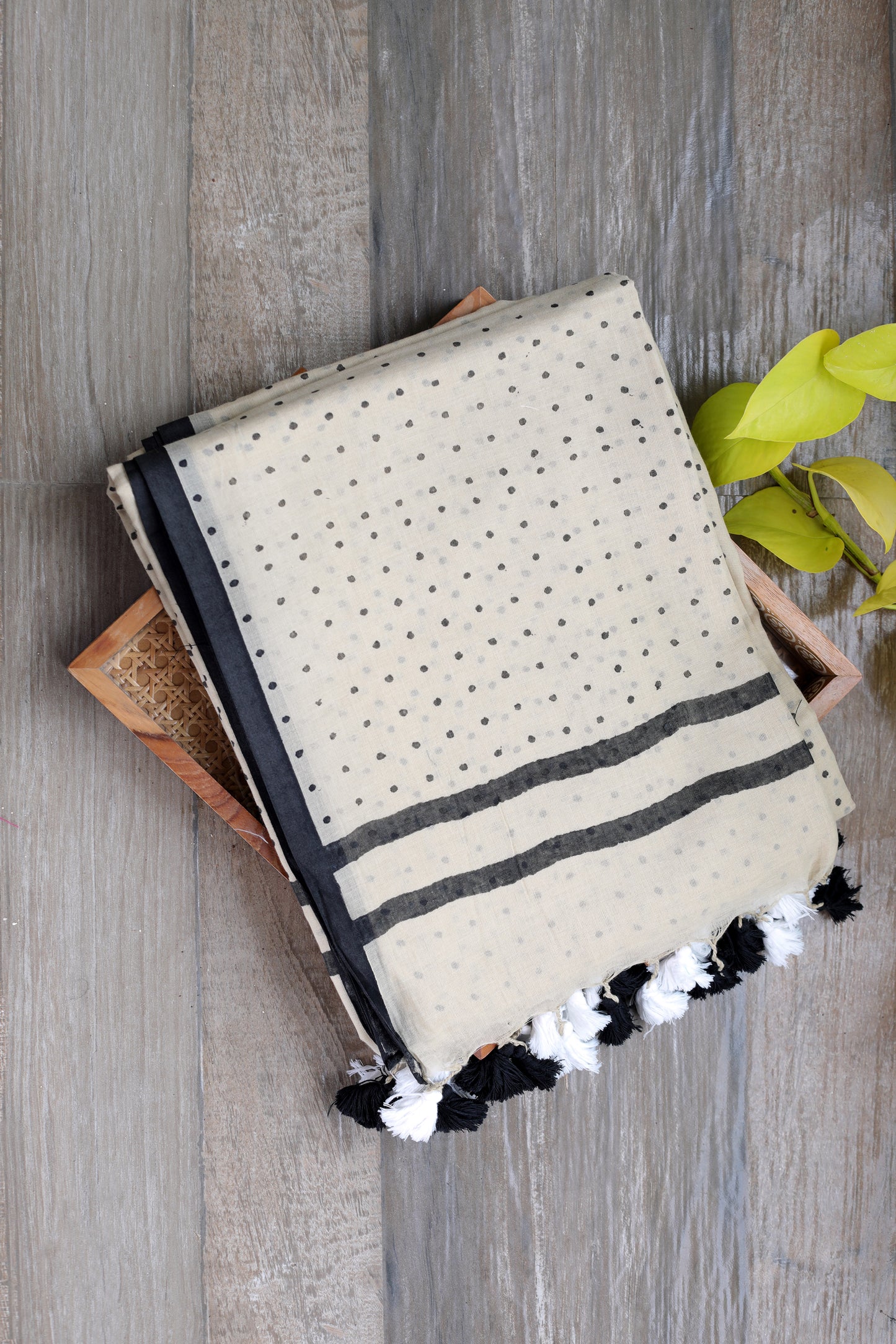 mul cotton in beige with bindi like polka dots in black with a black border and black and white tassles in the pallu