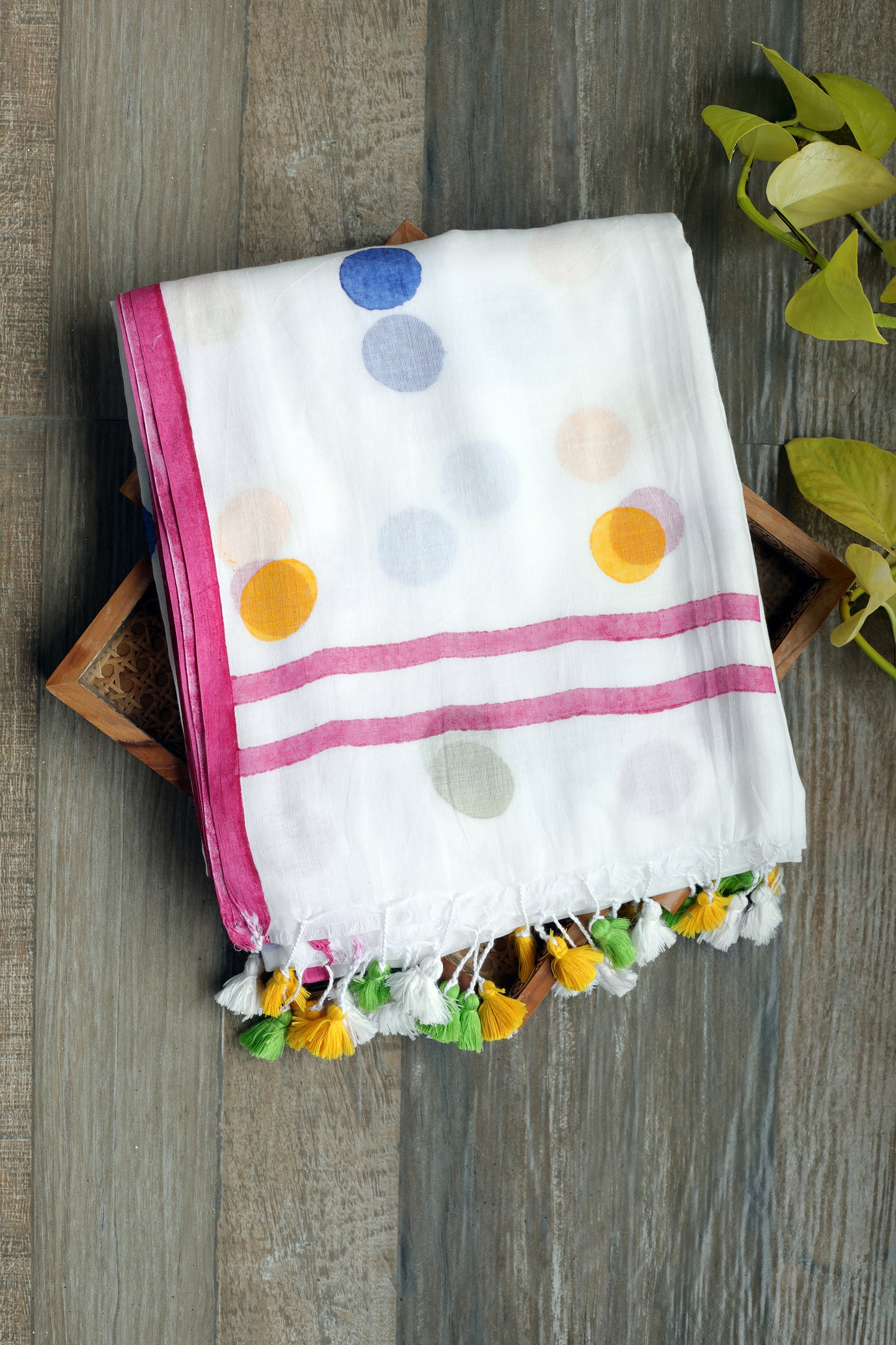 this saree is a breezy celebration of playfulness and poise. this milky white mul cotton saree is dotted with large, vibrant polka dots with pink border and colorful tassels