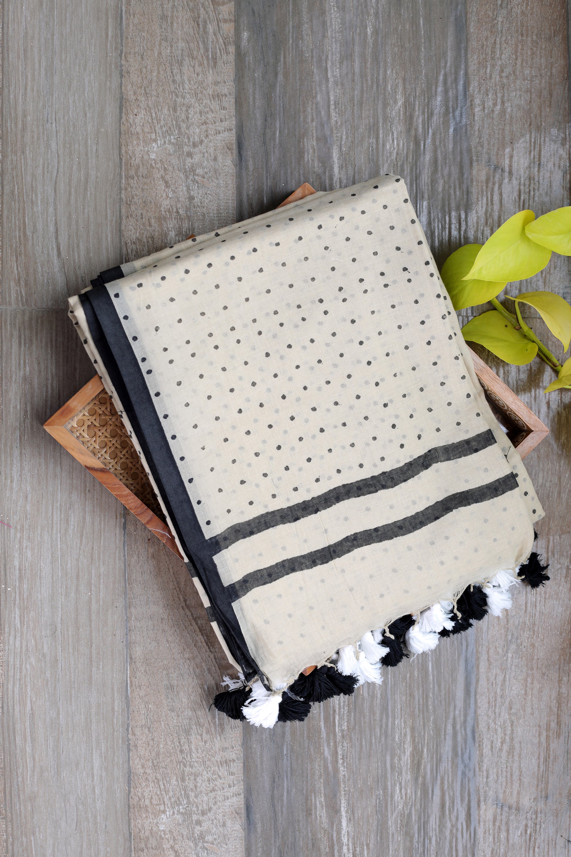 mul cotton in beige with bindi like polka dots in black with a black border and black and white tassles in the pallu